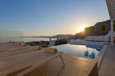 a view of a building with a pool and the sunset at Villa Mimosa in Pefkos (Lindos area) in Líndos