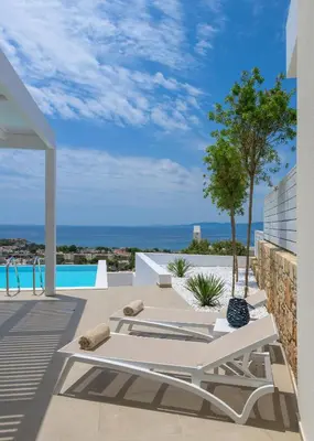 a patio with a white table and a view of the ocean at Villa Mimosa in Pefkos (Lindos area) in Líndos