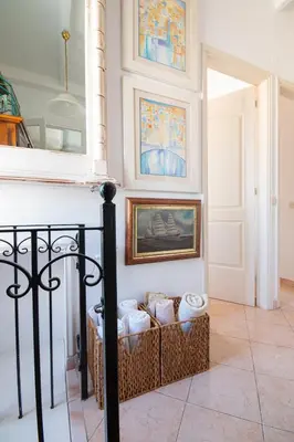 a room with a staircase with a chair and paintings on the wall at Villa Panorama in Symi