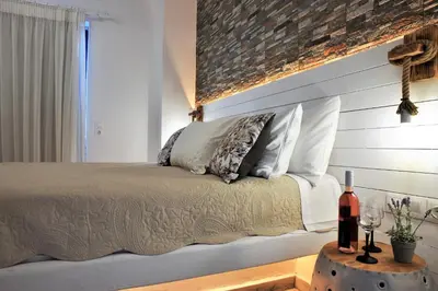 a bedroom with a bed with white pillows and a brick wall at Rafael Hotel-Adults Only in Líndos