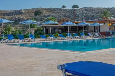 a swimming pool with blue chairs and umbrellas at Rafael Hotel-Adults Only in Líndos