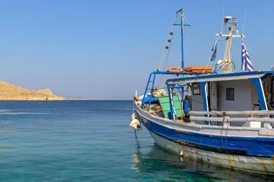 a blue boat is docked in the water at Anastasia house in Halki