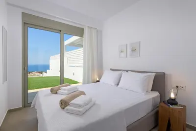 a bedroom with a white bed with towels on it at Villa Dione in Pefkos, Lindos area in Líndos