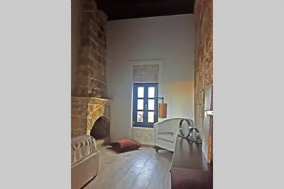 a living room with a stone fireplace and a table at Casa Quindici in the Old Town in Rhodes Town