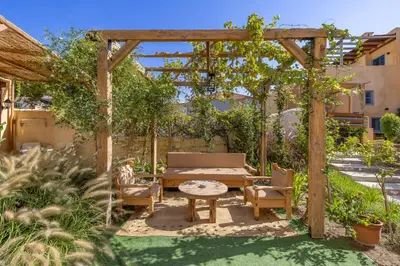 a garden with a wooden pergola with a bench and a table at Casa del Sol Suites in Rhodes Town