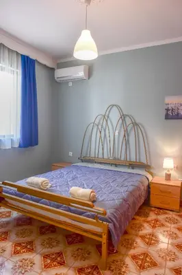 a bedroom with a bed with blue walls and a fan at villa62rodos in Kremasti