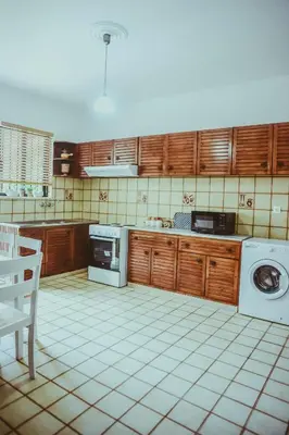 a kitchen with wooden cabinets and a washer and dryer at villa62rodos in Kremasti