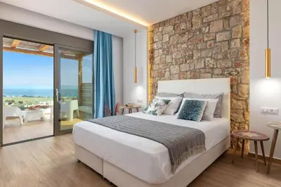 a bedroom with a large bed and a stone wall at Ikaros Villa in Pefki Rhodes