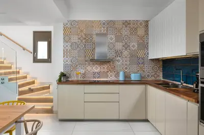a kitchen with white cabinets and a tile wall at Ikaros Villa in Pefki Rhodes