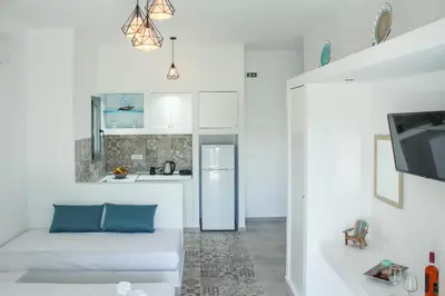 a white living room with a couch and a kitchen at Haraki Sea & Sun in Haraki