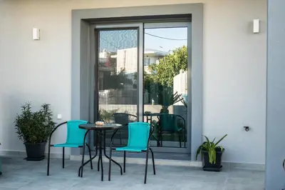 a patio with blue chairs and a table at Haraki Sea & Sun in Haraki