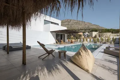 a villa with a swimming pool and a chair at Bianco Villa - Eve in Pefki Rhodes