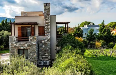 a house with a stone chimney in a yard at Villa Astravi in Ialyssos
