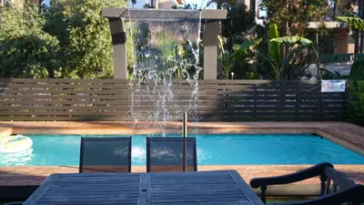 a fountain with two chairs and a table in front of a pool at Villa Astravi in Ialyssos