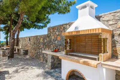 a stone wall with a pizza oven in a yard at Villa Summer Dawn in Kiotari
