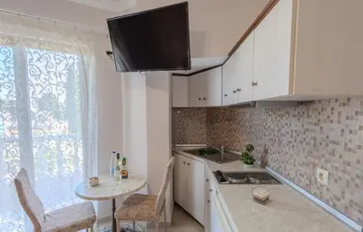 a kitchen with white cabinets and a table and a window at Knights' Castle Studios in Archangelos