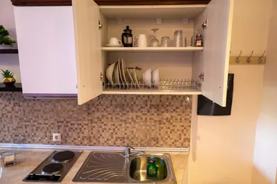 a kitchen with a sink and a shelf with dishes at Knights' Castle Studios in Archangelos