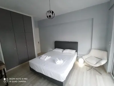 a bedroom with a white bed and a chair at Elli beach apartment top location Rodos in Rhodes Town