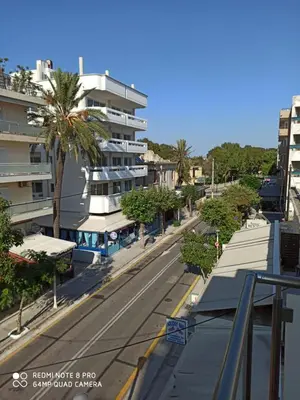an empty street with palm trees and a building at Elli beach apartment top location Rodos in Rhodes Town