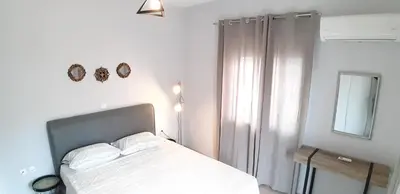 a white bedroom with a bed and a mirror at Elli beach apartment top location Rodos in Rhodes Town