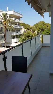 a balcony with a table and a palm tree and a building at Elli beach apartment top location Rodos in Rhodes Town
