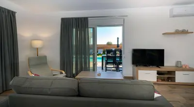 a living room with a couch and a television at Rosemary Rhodes Villa in Malona Village