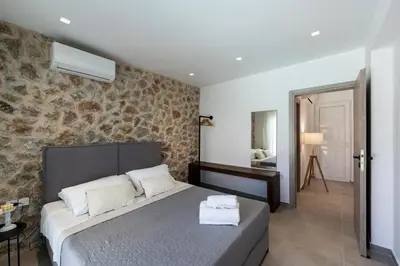 a bedroom with a bed and a stone wall at Rosemary Rhodes Villa in Malona Village