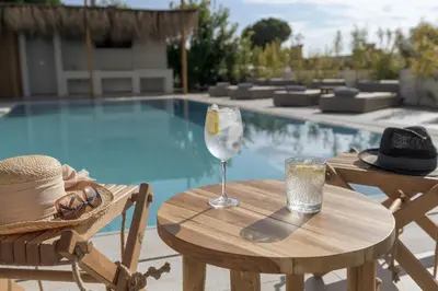 a table with a glass of wine next to a pool at Bianco Villa - Adam in Pefki Rhodes