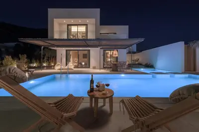 a large swimming pool in front of a house at night at Bianco Villa - Adam in Pefki Rhodes