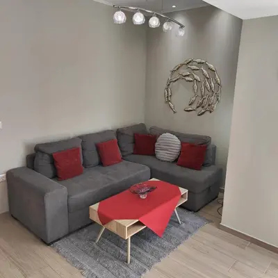 a living room with a gray couch with red pillows at Depie Luxury Apartment in Pastida Rhodes in Pastida