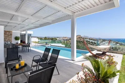 a patio with a table and chairs and a swimming pool at Villa Kastro in vlicha