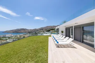 a row of white lounge chairs on the roof of a building at Villa Kastro in vlicha