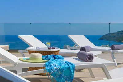 a group of white lounge chairs with hats and towels at Villa Akrotiri in vlicha