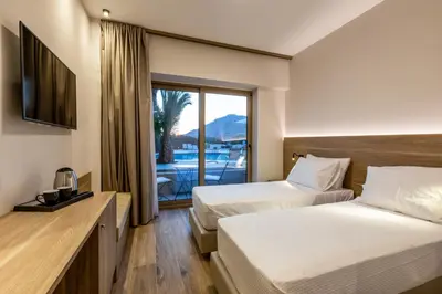 a hotel room with two beds and a balcony at White Olive Premium Lindos in Pefki Rhodes