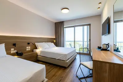 a hotel room with two beds and a television at White Olive Premium Lindos in Pefki Rhodes