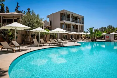 a swimming pool with chairs and umbrellas in front of a building at White Olive Premium Lindos in Pefki Rhodes