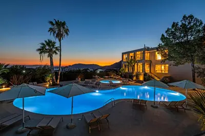 a pool with chairs and umbrellas in front of a hotel at White Olive Premium Lindos in Pefki Rhodes