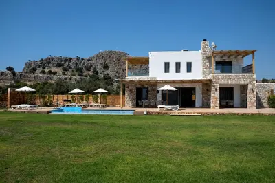 a stone house with a pool and a mountain at Villa Alkyoni Lindos in Líndos