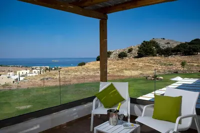 a balcony with white chairs and a view of the ocean at Villa Alkyoni Lindos in Líndos