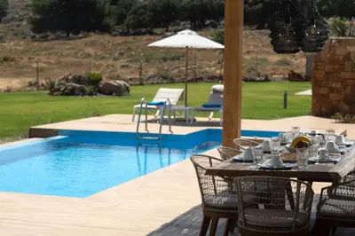 a table and chairs next to a swimming pool at Villa Alkyoni Lindos in Líndos