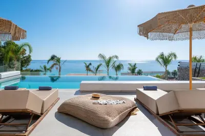 a pool with chairs and umbrellas and the ocean at Lido Blue Villa in Pefki Rhodes
