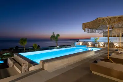 a swimming pool with a view of the ocean at night at Lido White Villa in Pefki Rhodes