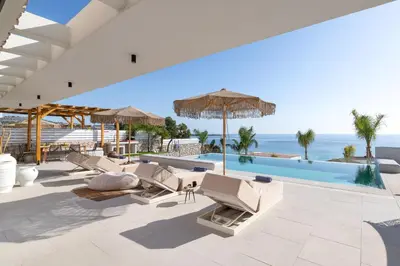 a pool with chairs and umbrellas and the ocean at Lido White Villa in Pefki Rhodes