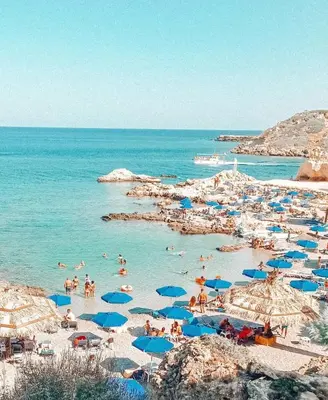 a group of people on a beach with blue umbrellas at Grande Blue Suites with private bay in Archangelos