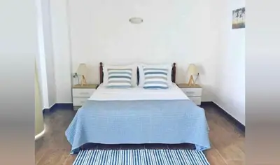 a bedroom with a bed with blue and white sheets at Grande Blue Suites with private bay in Archangelos