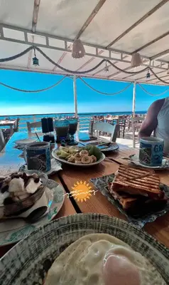 a table with plates of food on the beach at Grande Blue Suites with private bay in Archangelos