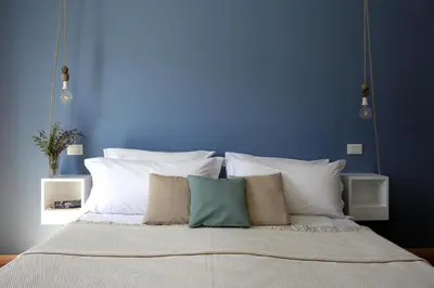 a bed with white pillows and a blue wall at Limani Life in Symi