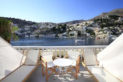 a balcony with a table and chairs on a boat at Limani Life in Symi