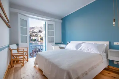 a bedroom with a large bed and a blue wall at Limani Life in Symi