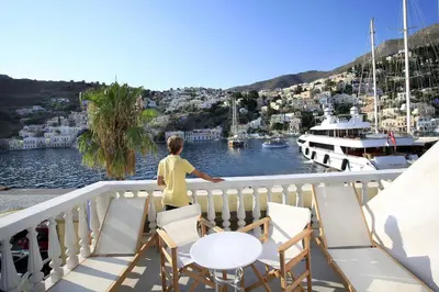 a boy standing on a balcony overlooking a marina at Limani Life in Symi